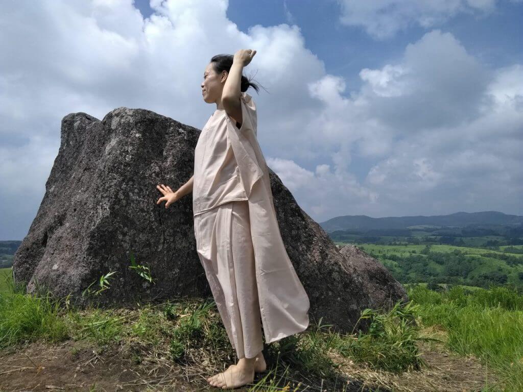 TAKSU AMANATのお洋服を着て丘に立つ女性